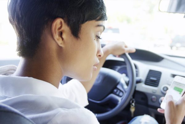Get Serious About Distracted Driving - Woman Looking Down At Cell Phone While Sitting In Drivers Seat In Traffic